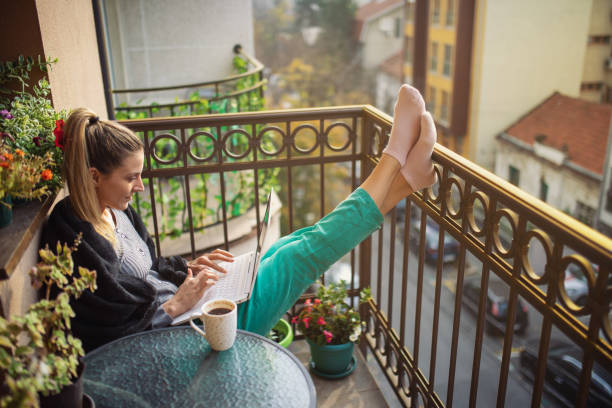 istock Young woman using laptop on balcony at morning 1355539068
