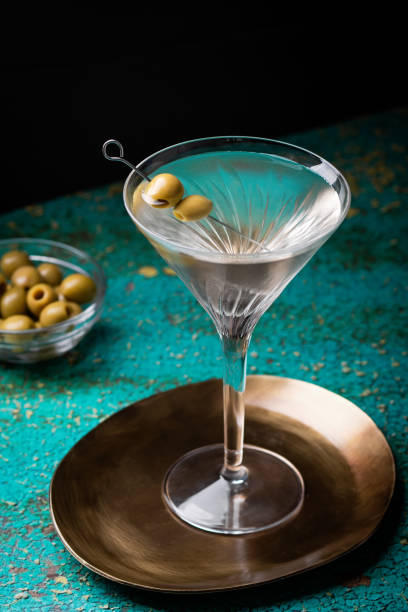 緑の色のテーブルにオリーブを飾ったマティーニグラスの汚れたマティーニカクテル - martini martini glass dirty martini olive ストックフォトと画像