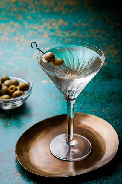 緑の色のテーブルにオリーブを飾ったマティーニグラスの汚れたマティーニカクテル - martini martini glass dirty martini olive ストックフォトと画像