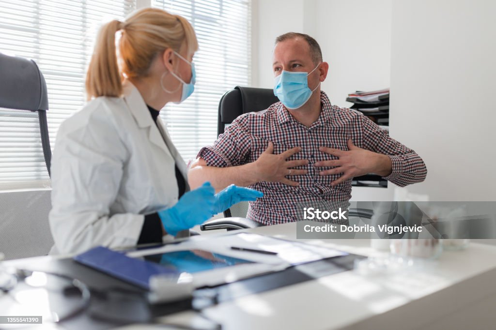 Patient touching torso when talking to female doctor Cardiologist listening a patient concerned about chest pain Heart - Internal Organ Stock Photo