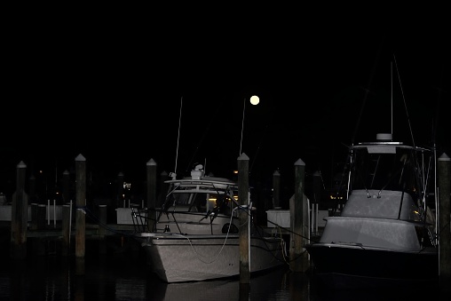 Fishing and recreational boats in the West Ocean City, MD harbor at dusk with a full moon rising