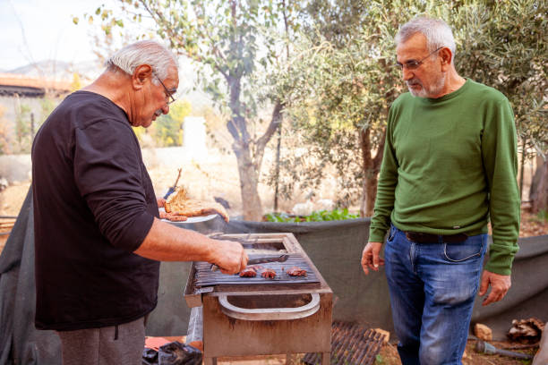 Father and son at the barbecue fire making sausage stock photo
