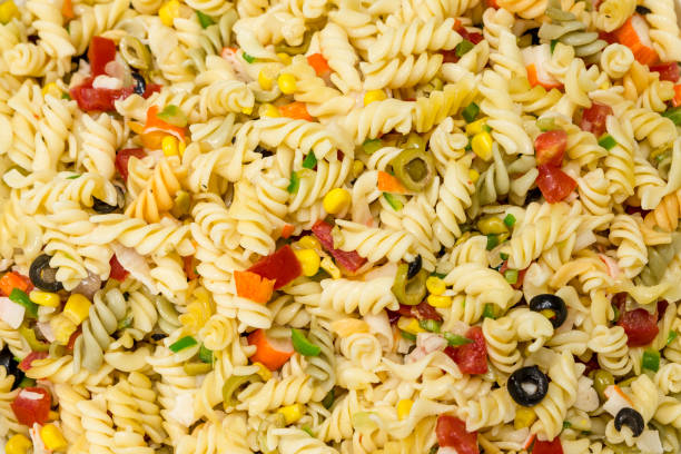 istock Pasta salad background with black olives, corn, peppers and surimi 1355542813