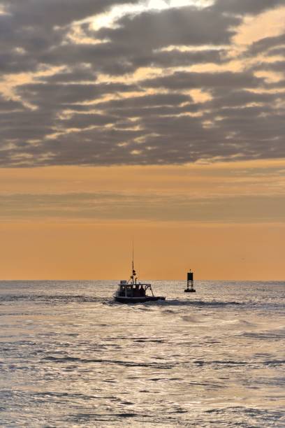 A fishing boat sailing out of the Ocean City, Maryland harbor at dawn bound for the Atlantic Ocean