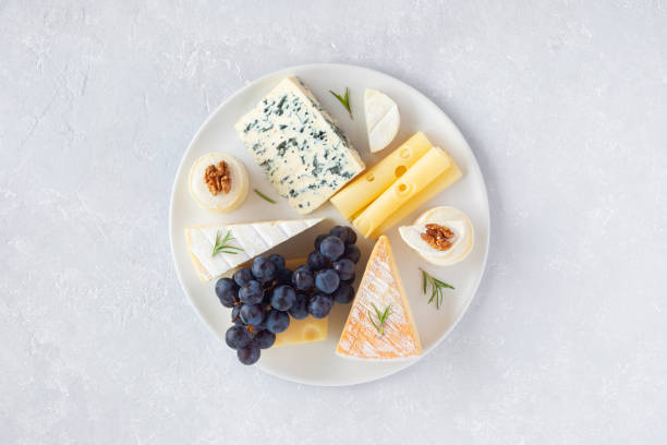 istock Cheese plate served with grapes and walnuts on a grey concrete background 1355547640