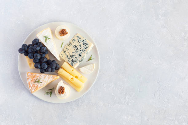 istock Cheese plate served with grapes and walnuts on a grey concrete background 1355547643