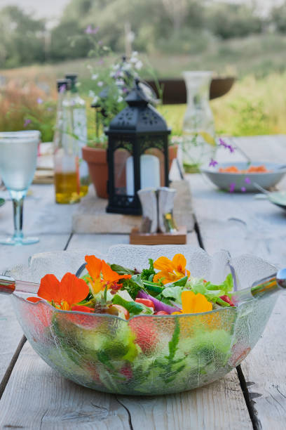 Fresh salad in a glass bowl with nasturtium flowers outdoors in the countryside Fresh salad in a glass bowl with nasturtium flowers outdoors in the countryside tropaeolum majus garden nasturtium indian cress or monks cress stock pictures, royalty-free photos & images