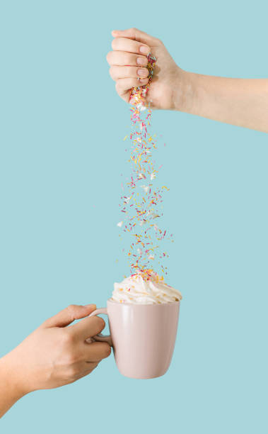 istock Real life composition. Two hands , one pink mug with coffee and cream. Unicorn sprinkles on colored background. 1355547896