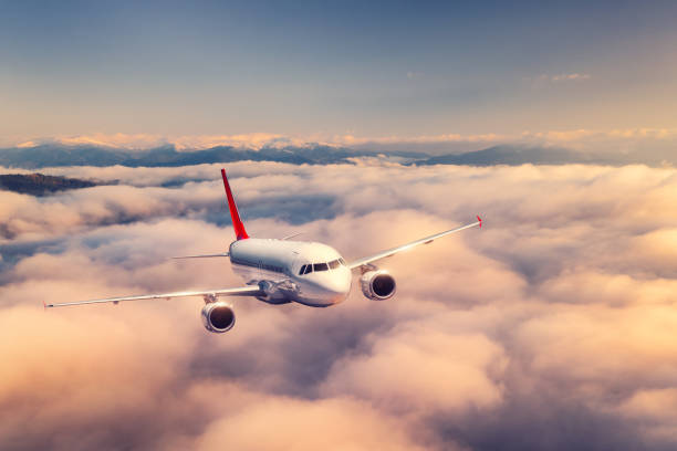 飛行機は夏の日没時に雲の上を飛んでいる。旅客機、美しい雲、山、空と風景。航空機が離陸する ビジネス旅行民間機。輸送 - airplane taking off sky commercial airplane ストックフォトと画像