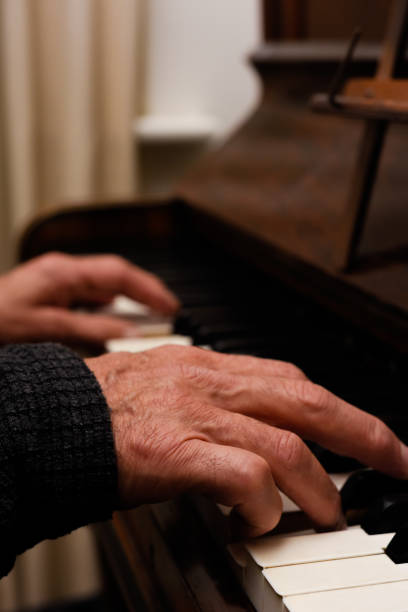 istock Mature male hands playing piano with focus on hands and keyboard 1355548998