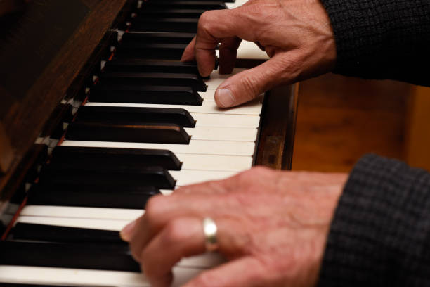 istock Mature male hands playing piano with focus on hands and keyboard 1355549030