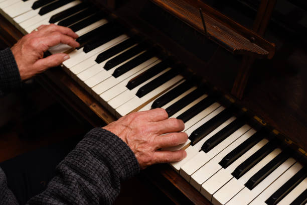 istock Mature male hands playing piano with focus on hands and keyboard 1355549606