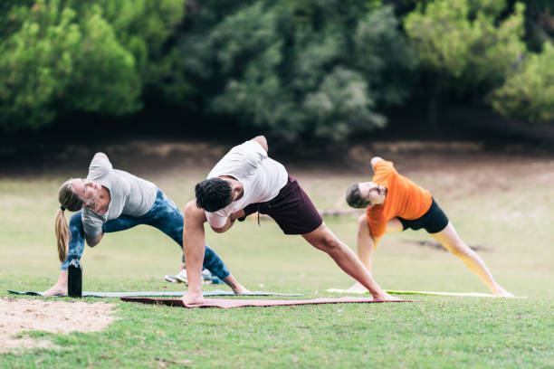 istock Group of people practising yoga on a park 1355554737