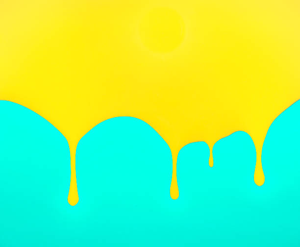 istock Dripping yellow paint on turquoise blue background 1355557242