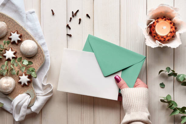 istock Blank postcard in hand. Winter holiday greeting card mockup. Eucalyptus, tea light in pomander ball 1355558594