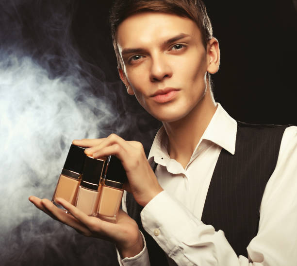 young male make up artist posing with foundation for make-up o - male beauty male 2000 style imagens e fotografias de stock