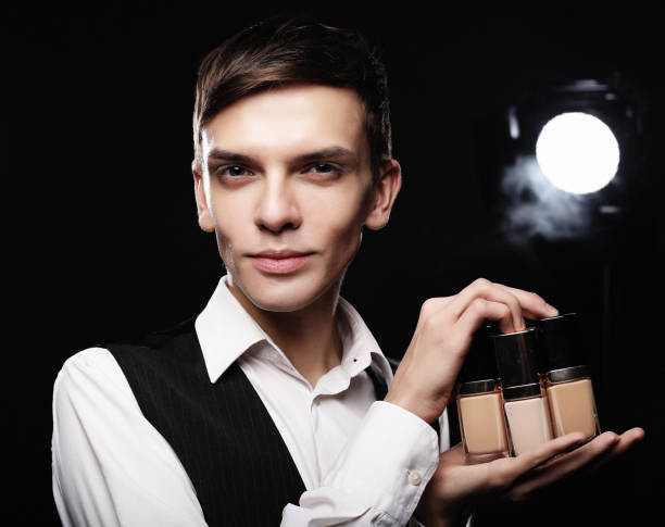 young male make up artist posing with foundation for make-up o - male beauty male 2000 style imagens e fotografias de stock