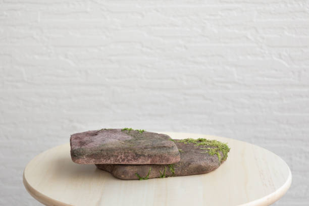 istock Flat natural stones with sprouted moss on white wall background. Abstract minimal scene with podiums. Mockup template for product. 1355578072