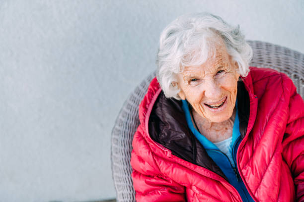 cheerful 100-year-old elderly senior caucasian woman sitting and laughing outdoors in the winter - 110 imagens e fotografias de stock