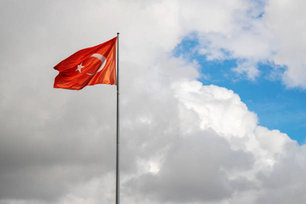 istock Waving turkish flag on flagpole. Blue sky and storm clouds. 1355587991