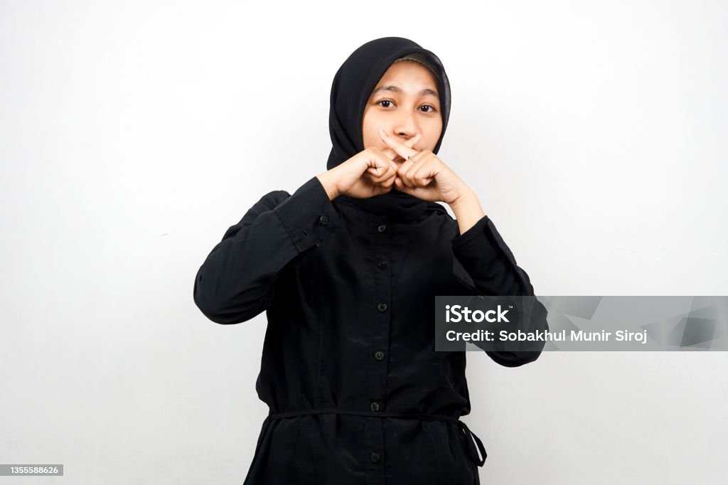 Beautiful asian young muslim woman with finger on mouth, telling to be quiet, don't make noise, lower your voice, don't talk, isolated on white background 20-24 Years Stock Photo