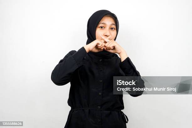 Beautiful Asian Young Muslim Woman With Finger On Mouth Telling To Be Quiet Dont Make Noise Lower Your Voice Dont Talk Isolated On White Background Stock Photo - Download Image Now