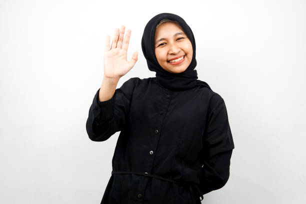 Beautiful and cheerful young asian muslim woman, with open palms, saying hello, how are you, isolated on white background stock photo