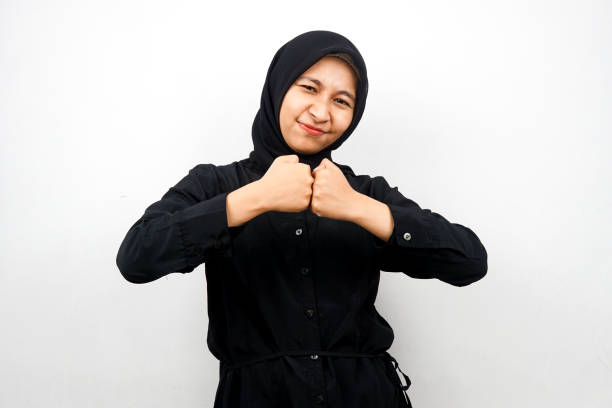 Beautiful and cheerful young asian muslim woman, with clenched hands, victory, isolated on white background stock photo
