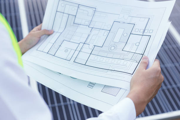 istock Engineer open blueprint of solar farm project on solar cells panel 1355590345