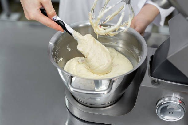 o confeiteiro adiciona farinha à tigela da batedeira. - cake making mixing eggs - fotografias e filmes do acervo