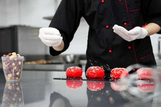istock The pastry chef sprinkles the red mousse cake with sesame seeds. 1355597372