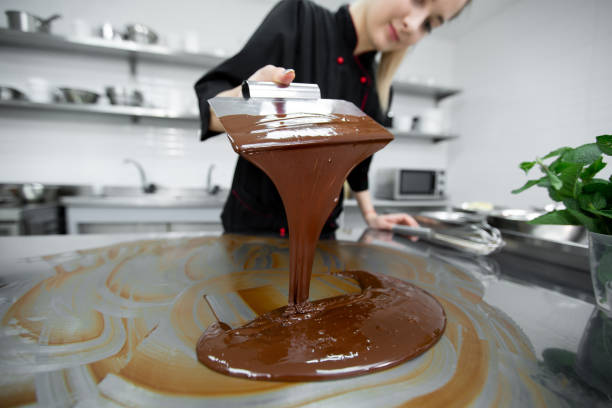 Close-up of a pastry chef using spatulas tempering molten chocolate