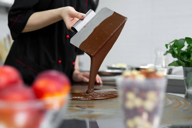istock Close-up of a pastry chef using spatulas tempering molten chocolate 1355597590