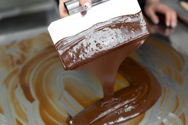istock Close-up of a pastry chef using spatulas tempering molten chocolate 1355597624