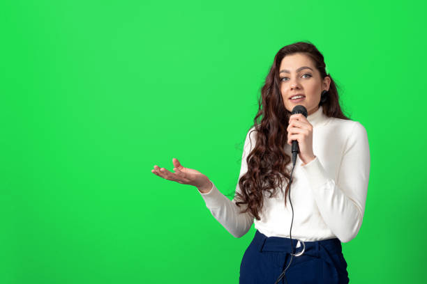 istock attractive female conference speaker during presentation, holds microphone and makes some gestures 1355600323
