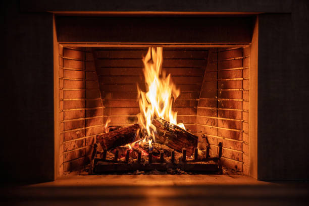 fireplace burning firewood, fire flames on wood logs, bricks background. cozy warm home at christmas - şömine stok fotoğraflar ve resimler