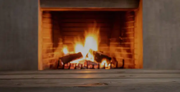 Photo of Table on blur burning fireplace background. Empty wooden planks, space.