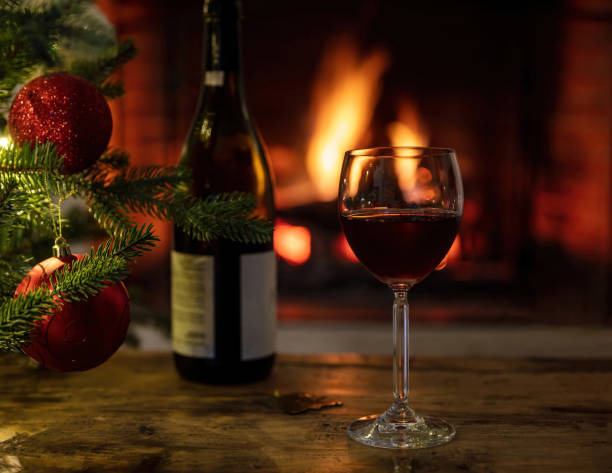 istock Red wine glass, burning fireplace background. Christmas tree decoration 1355602801