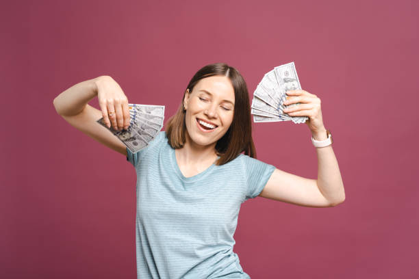 istock Happy woman holding dollars on pink background 1355604556