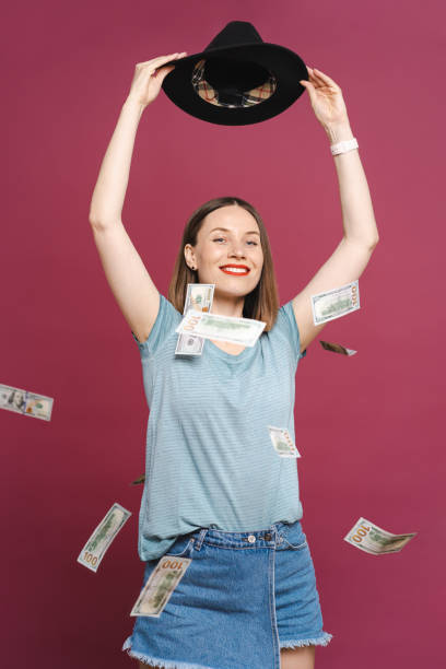 istock Woman playing with money on pink background 1355604819