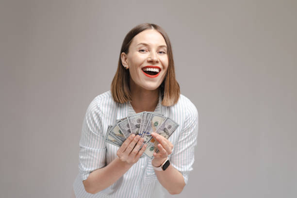 istock Happy woman holding dollars on gray background 1355604861