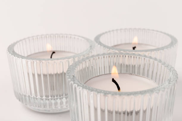 istock Burning tea candles in a glass holder, isolated on white. Space for text 1355606388