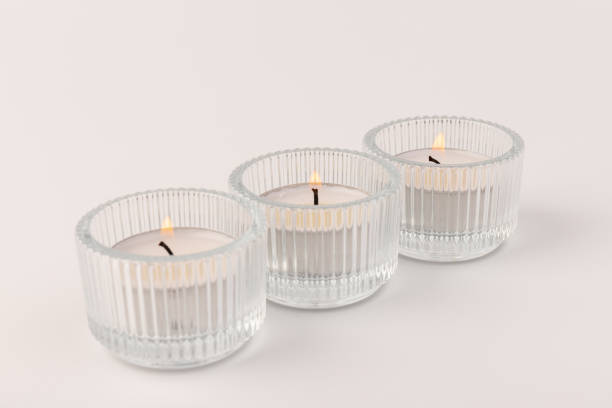 istock Burning tea candles in a glass holder, isolated on white. Space for text 1355606393