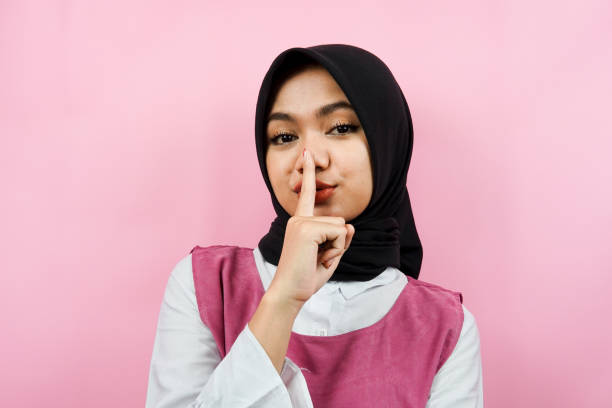 Closeup of a beautiful young Muslim woman shh, forbidden to talk, please be quiet, isolated stock photo