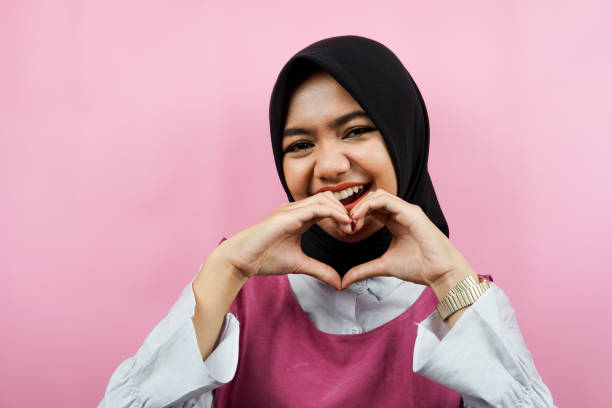Closeup of beautiful young Muslim woman with love hands, i love you, isolated stock photo