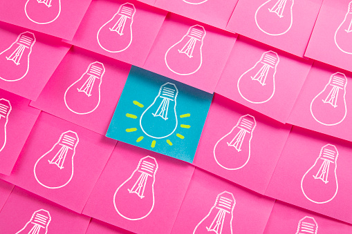 Many light bulbs drawn on pink and purple colored adhesive notes