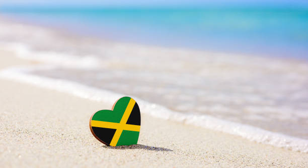 flagge der jamaika in form eines herzens an einem sandstrand. - jamaica stock-fotos und bilder