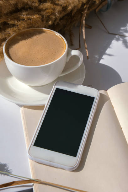 istock Pampas grass and white cup with coffee. Mobile phone with black screen. Checking social media Drinking Cappuccino in the breakfast morning at home. Flat lay. Wallpaper. Aesthetics 1355615106