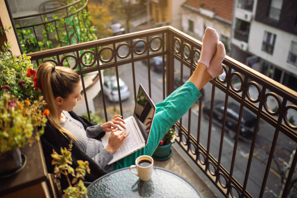 istock Young woman using laptop on balcony at morning 1355617390