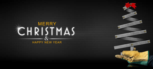 Hand with protective work glove holding a small metallic ruler in the shape of a Christmas tree with a red comet star, on a black background with text Merry Christmas and Happy New Year.
